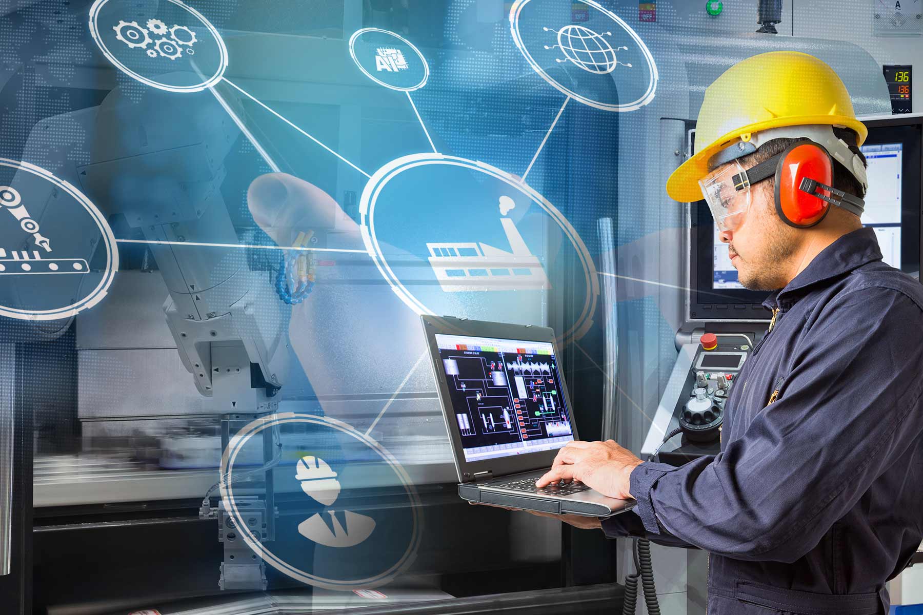 A man in a hardhat with a laptop simulating smart manufacturing.
