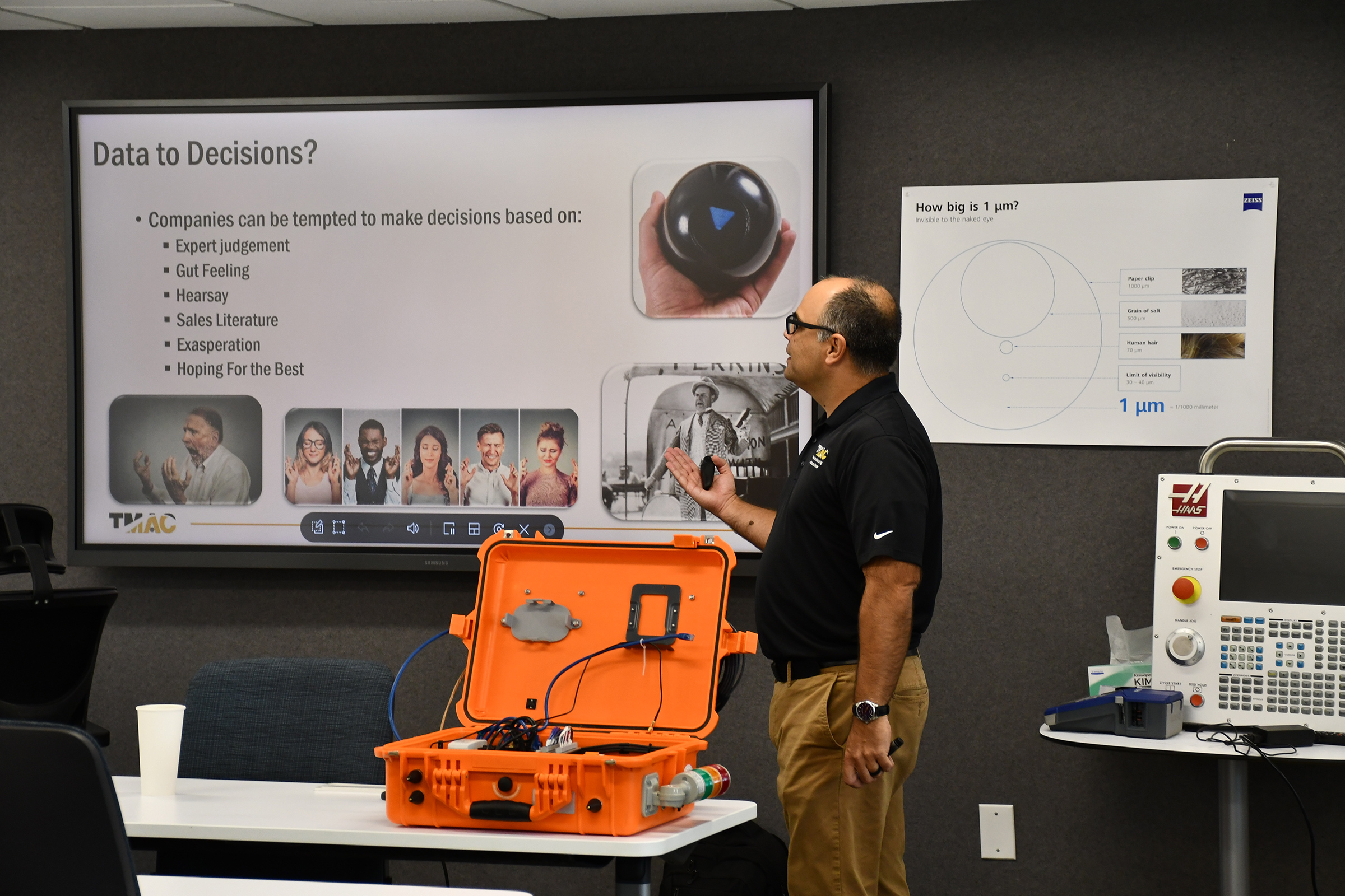 An instructor standing behind a large open orange container discussing a presentation slide that reads Data to Decisions?